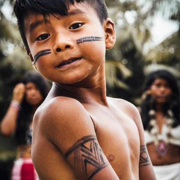 Indigenous boy with black stripes painted on his face.