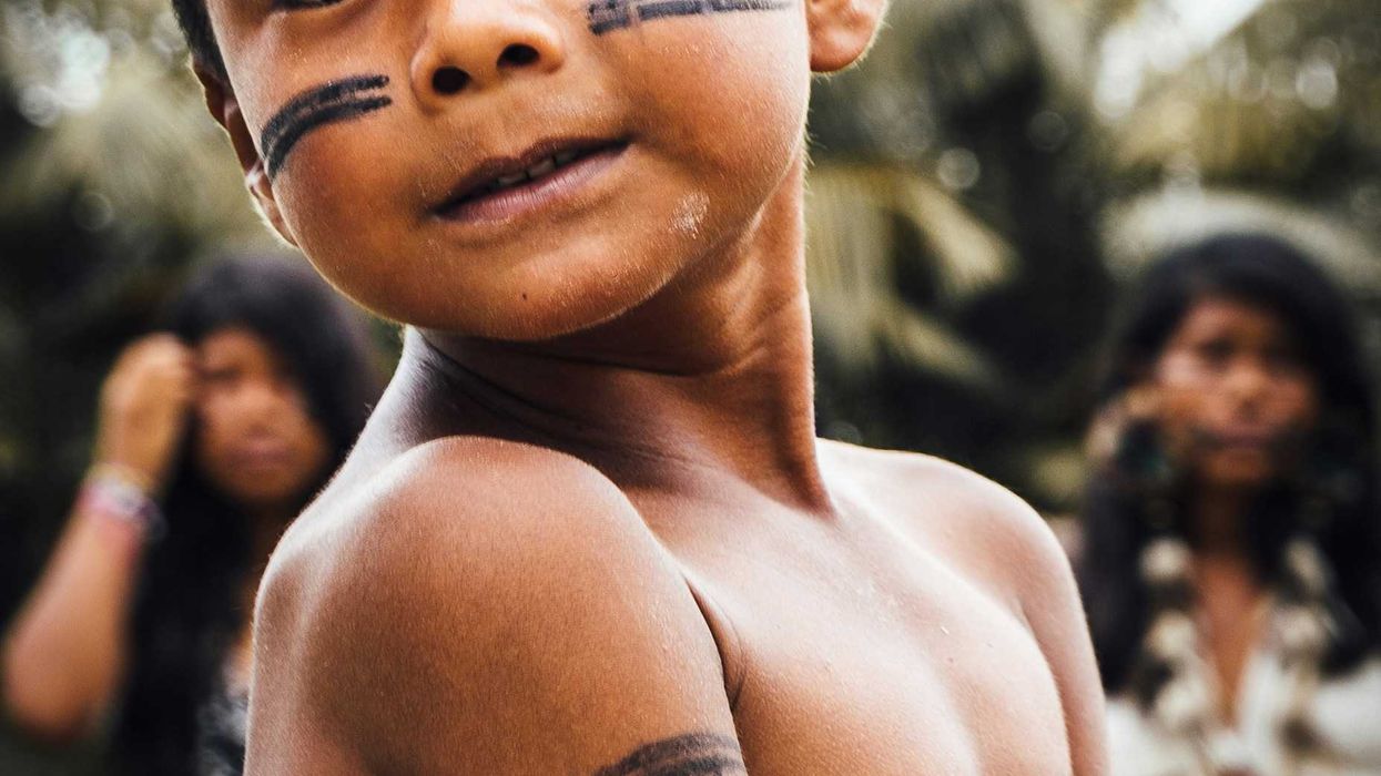 Indigenous child with black painted stripes on face.