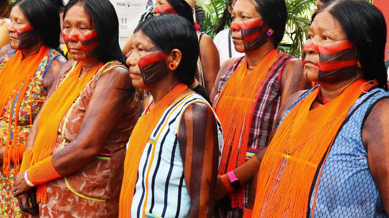 Indigenous women in Brazil with painted faces and orange scarves.