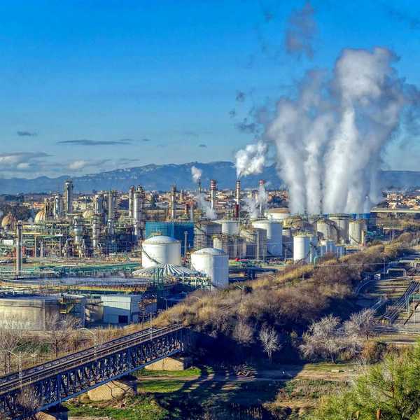 Industrial complex with polluting smoke rising from stacks.