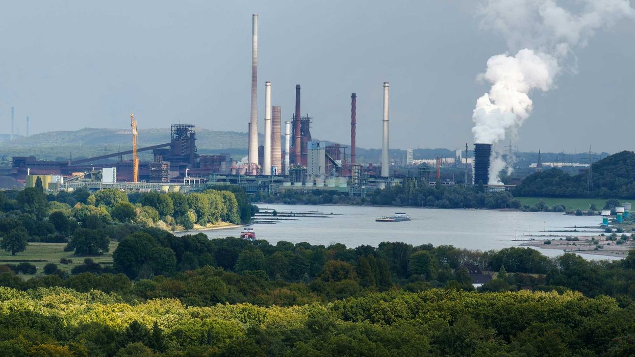 Industrial complex with smokestacks near a body of water.