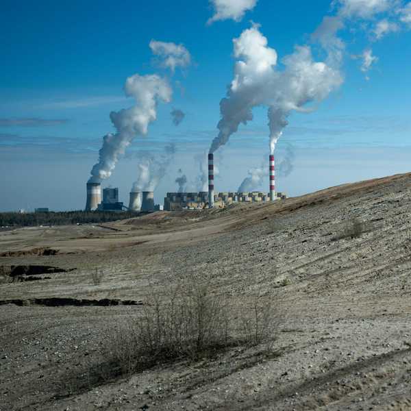 Industrial power plant with smoke stacks under blue sky.