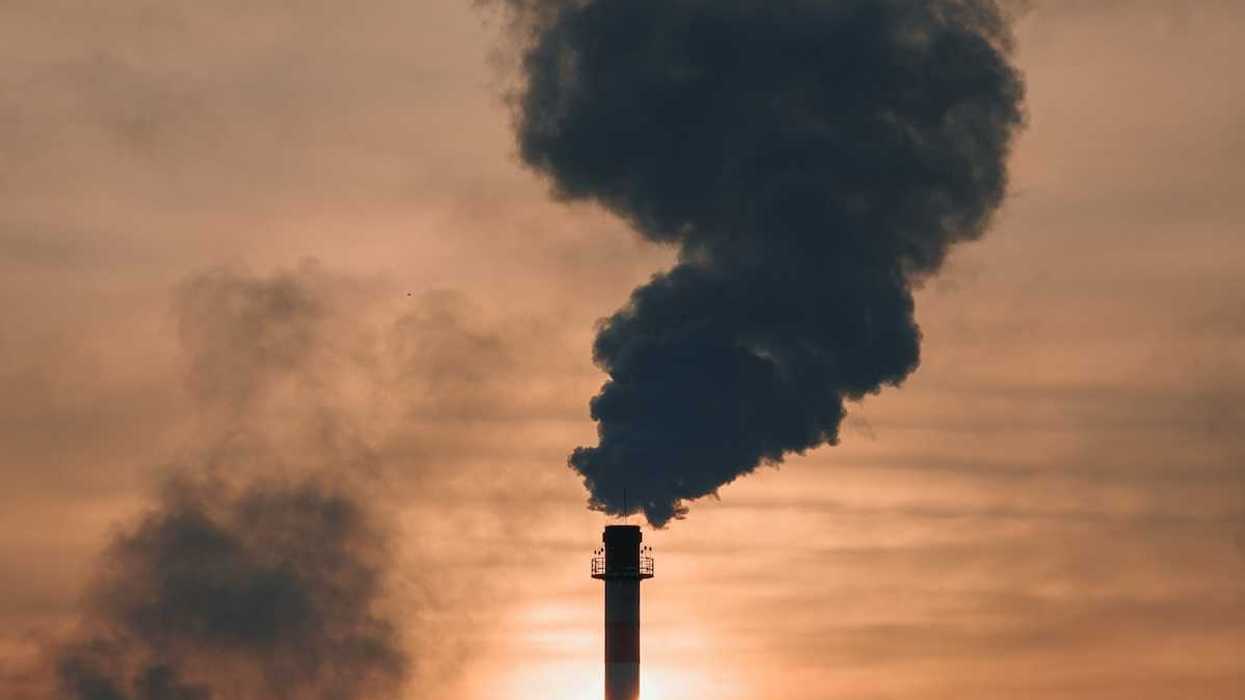 Industrial smokestack belching dark, sooty, smoke.