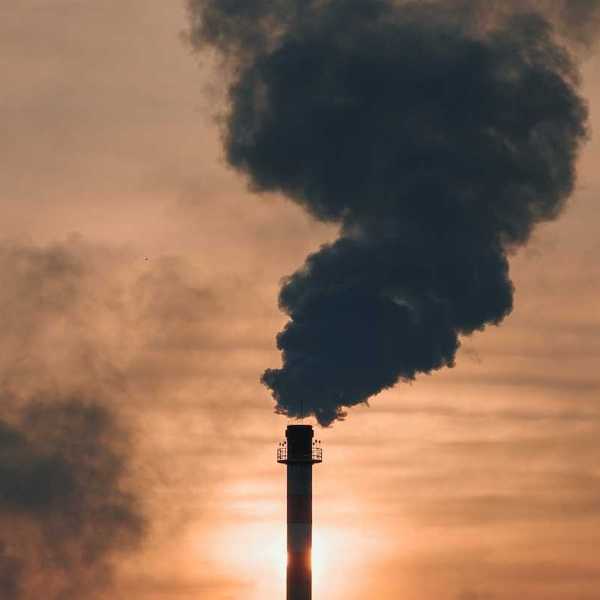 Industrial smokestack belching dark, sooty, smoke.