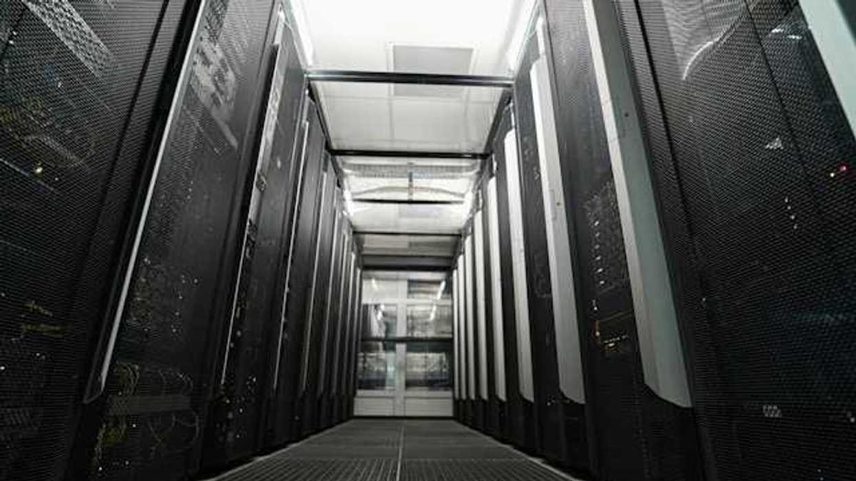 Inside of a data center with black computers on either side of a pathway to walk through