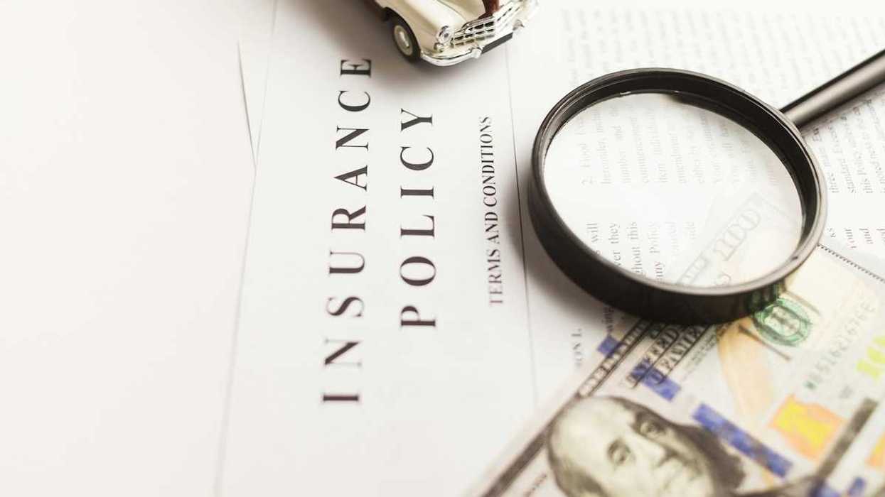 Insurance policy with magnifying glass, miniature auto, and hundred-dollar bill