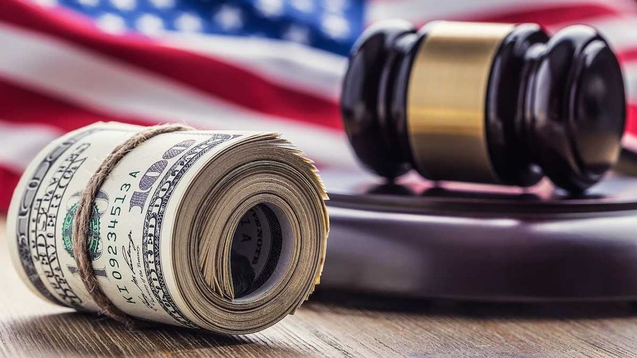 Judge's hammer gavel and rolled banknotes with USA flag in the background.