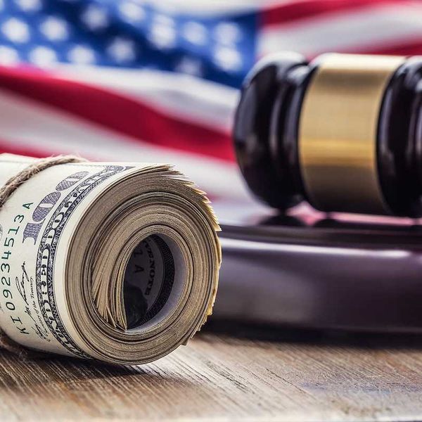 Judge's hammer gavel and rolled banknotes with USA flag in the background.