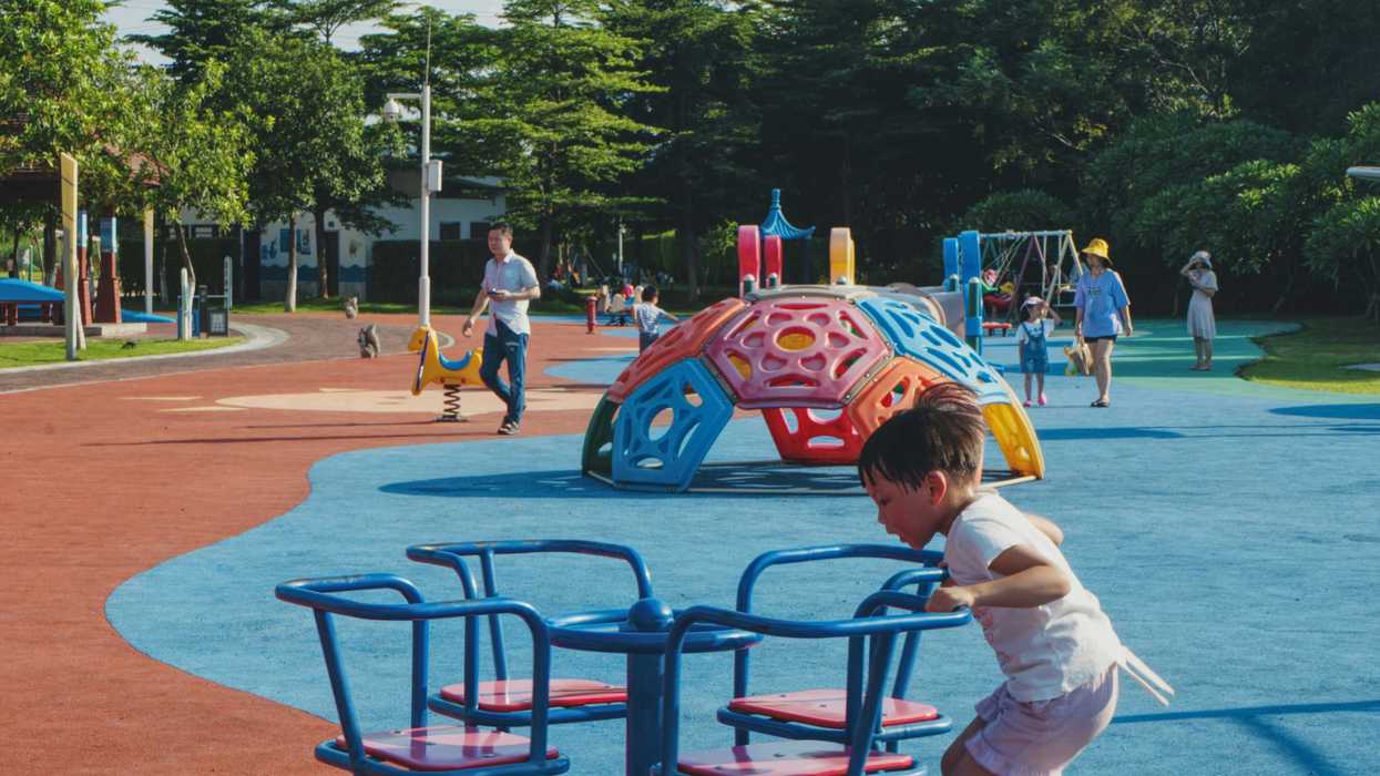 Kids play on a playground with a multicolored spongy surface.