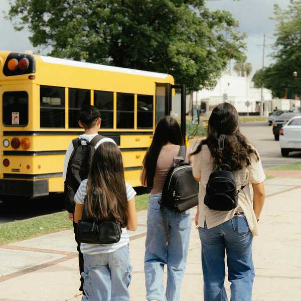 Kids walk to a school bus stop