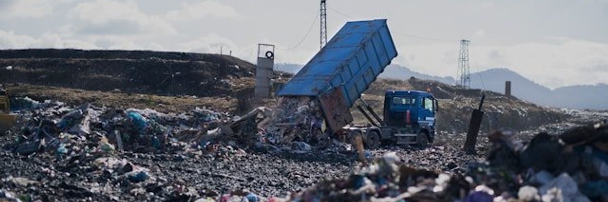 Landfill with truck dropping off a load of trash.