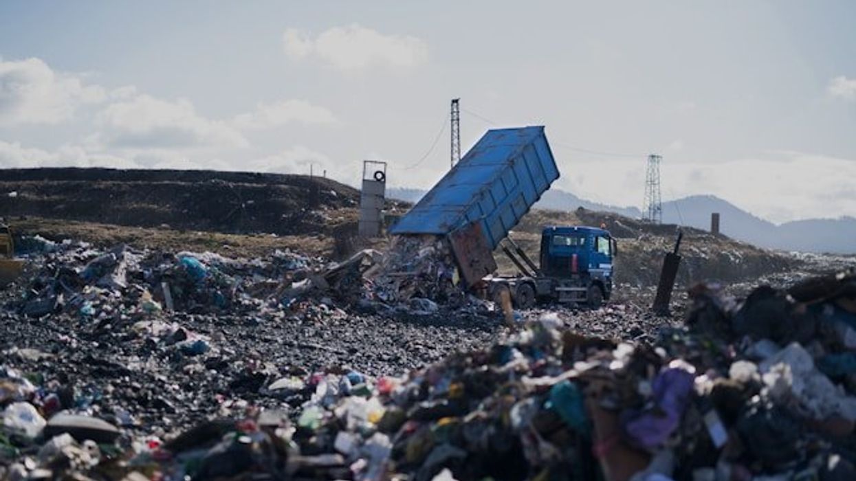Landfill with truck dropping off a load of trash.