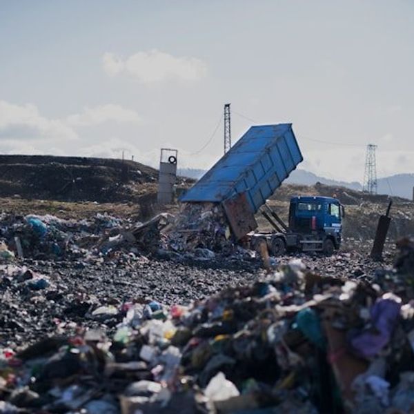 Landfill with truck dropping off a load of trash.