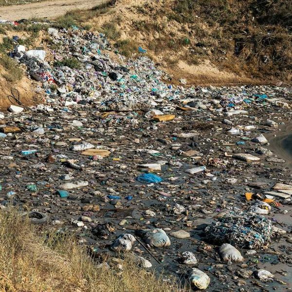 Large amount of trash dumped at roadside next to waterway