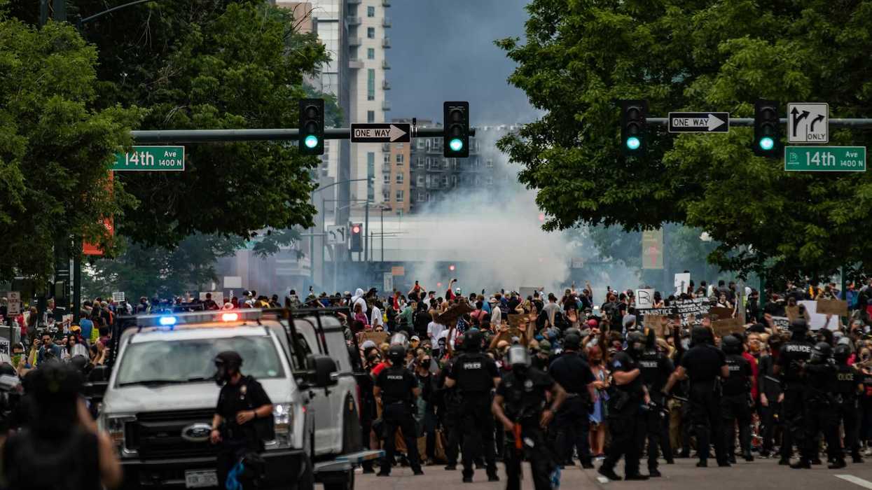 large crowd protesting with large police presence employing tear gas