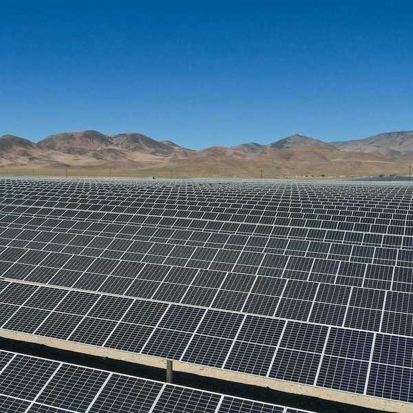 Large expanse of solar panels stretching out to distant hills.