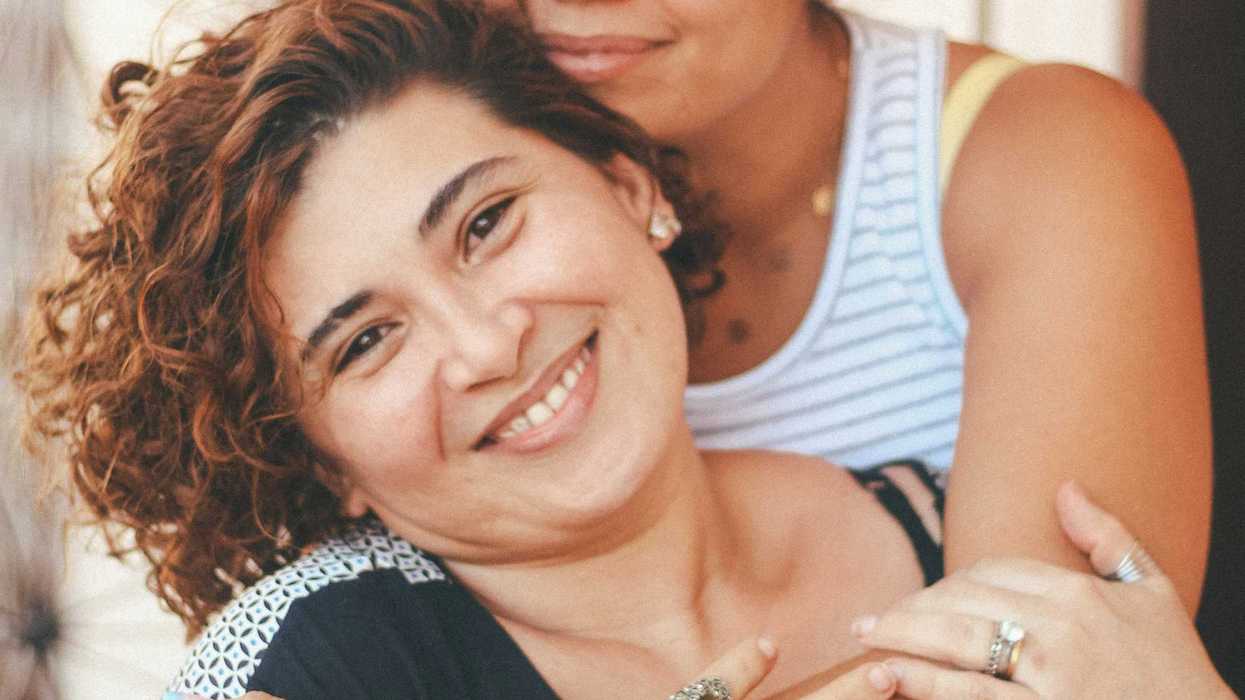 Latina woman in white tank top hugging older woman in blue tank top