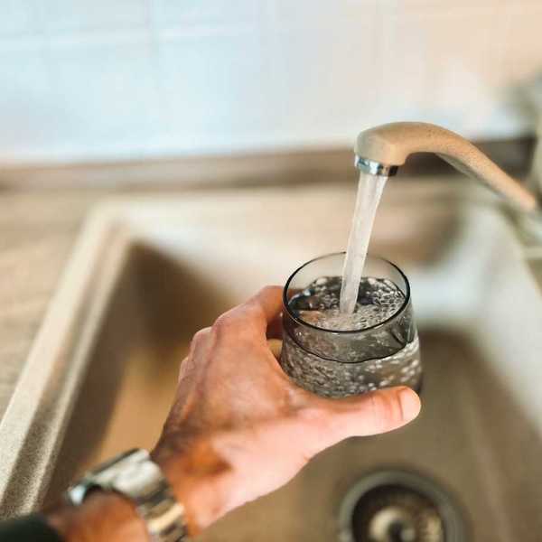 Left hand filling a water glass from the tap