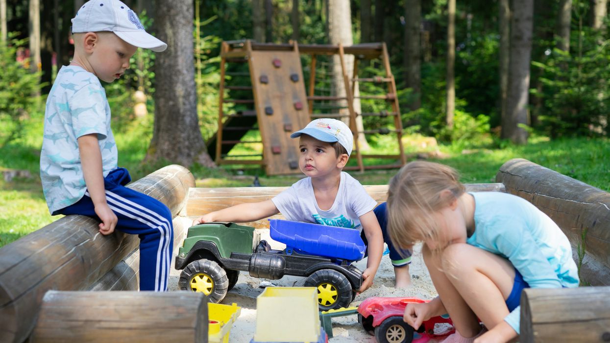 Little boys play with toy trucks in a sandbox
