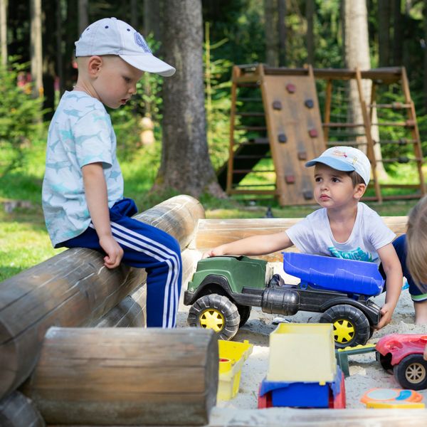 Little boys play with toy trucks in a sandbox