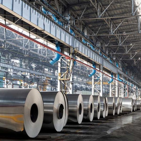 Long row of rolls of aluminum in production shop of plant.