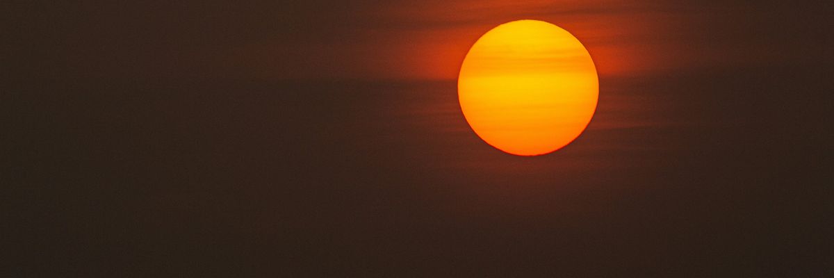 low-light photo of sun against a dark grey and orange sky.