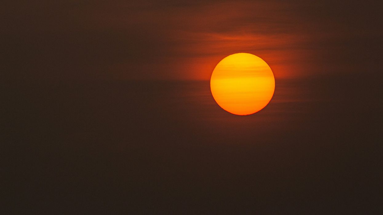 low-light photo of sun against a dark grey and orange sky.