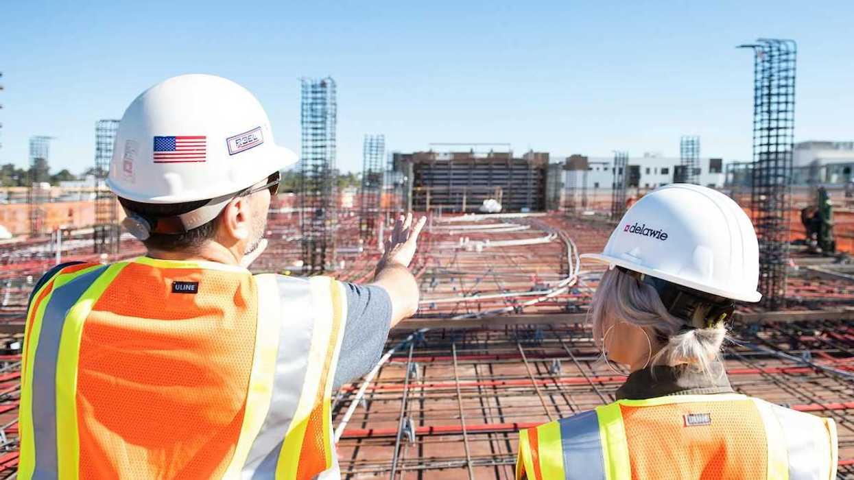 Man and woman in reflective vests reviewing a construction site