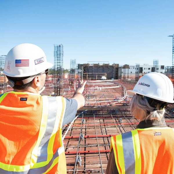 Man and woman in reflective vests reviewing a construction site