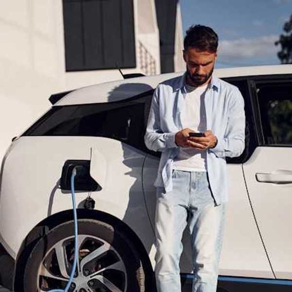Man checking his phone while waiting for his electric vehicle to charge