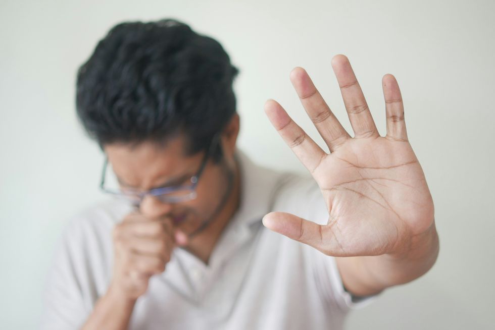 man coughing with hand outstretched