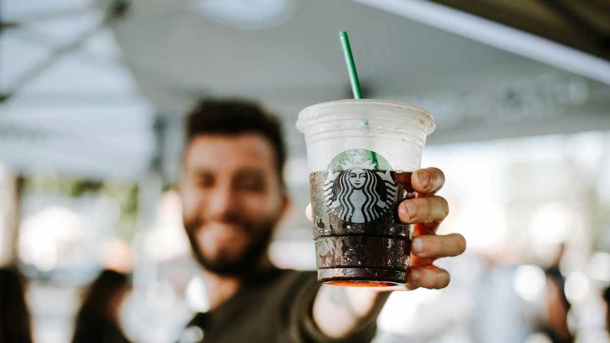 Man displaying a closeup of a Starbucks cold drink cup