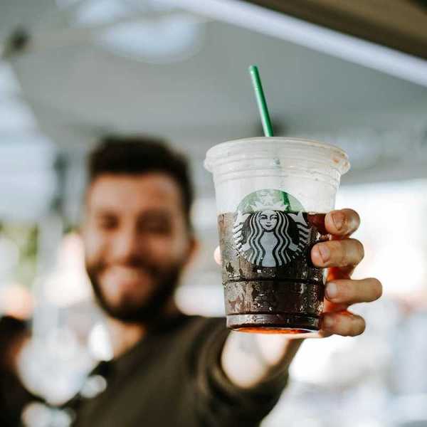 Man displaying a closeup of a Starbucks cold drink cup