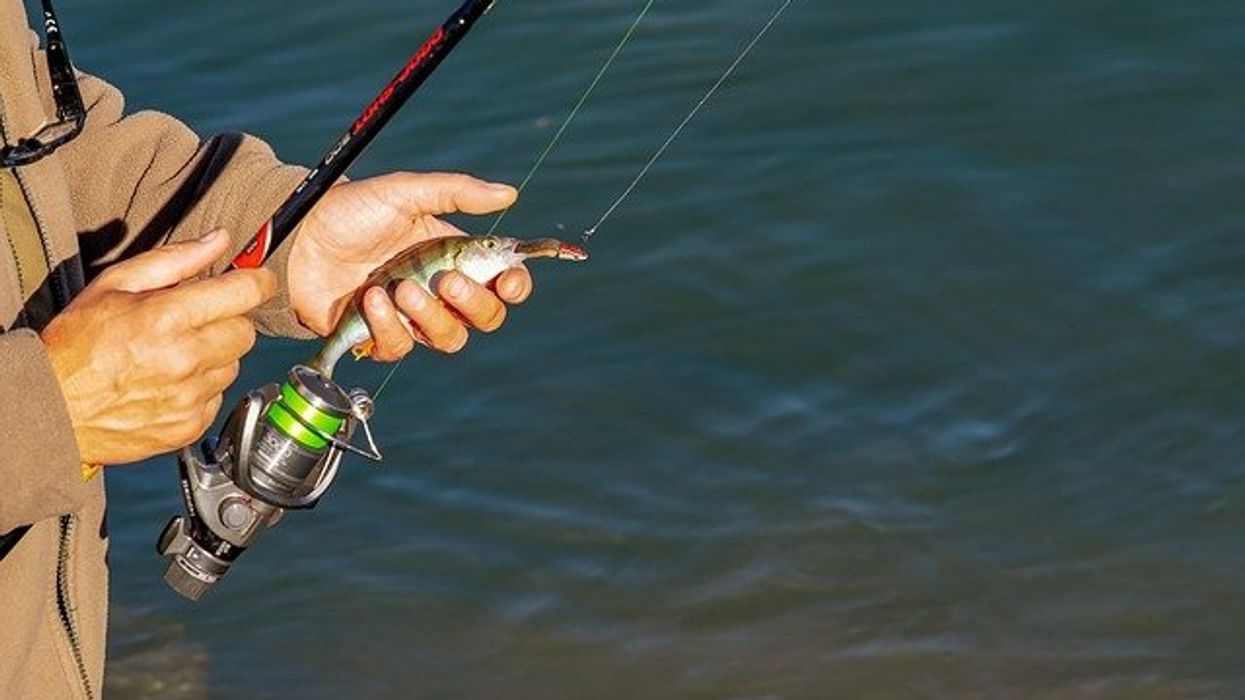 Man holding a fishing pole on the edge of a river.