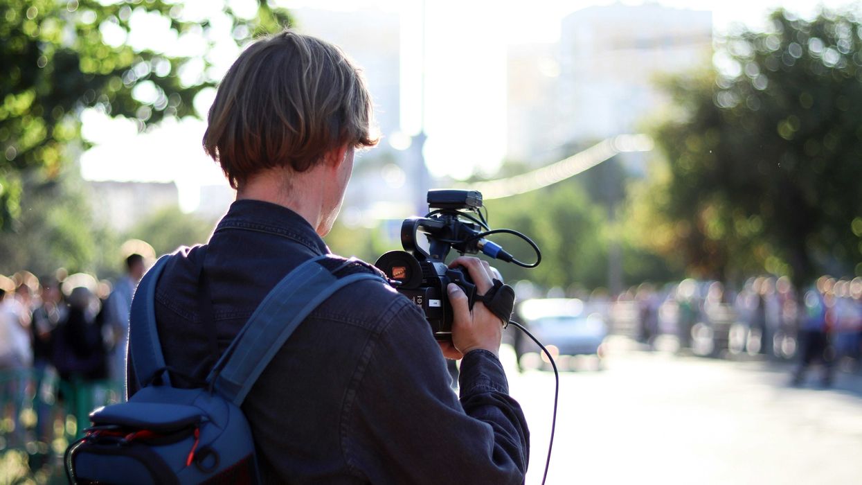 man in black jacket holding black dslr camera