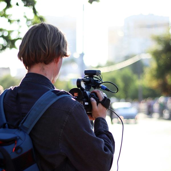 man in black jacket holding black dslr camera