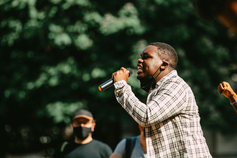 man in blue and white plaid dress shirt holding microphone.