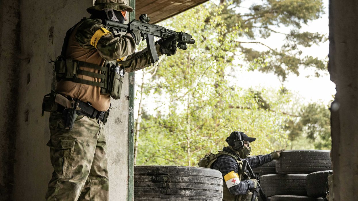 man in green and brown camouflage uniform carrying black backpack.