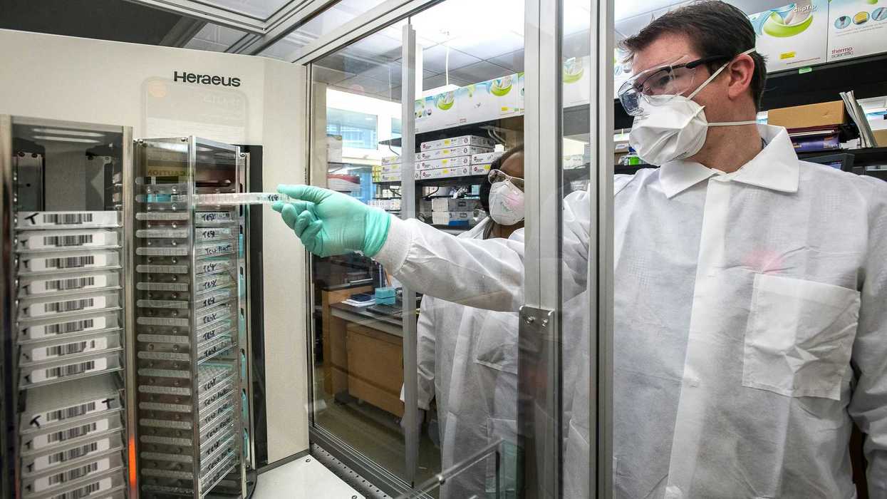 man in white scrub suit standing near glass window.