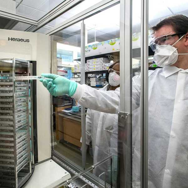 man in white scrub suit standing near glass window.