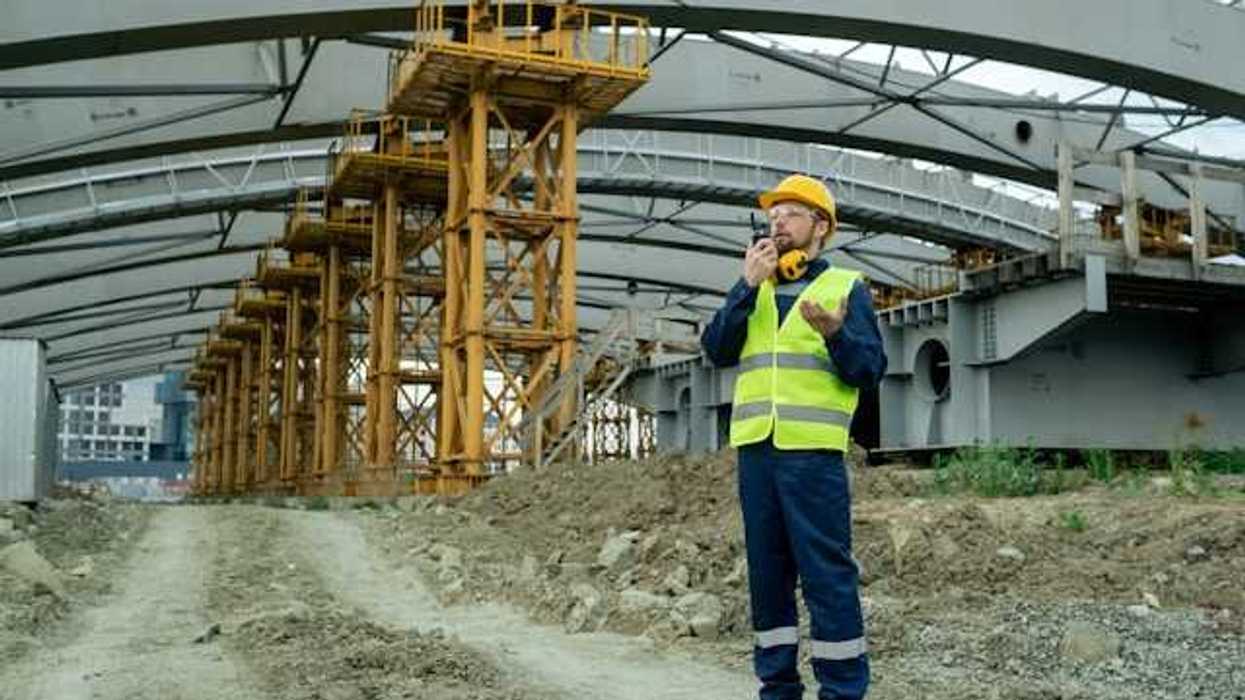 Man in yellow safety vest standing under a building roof being built