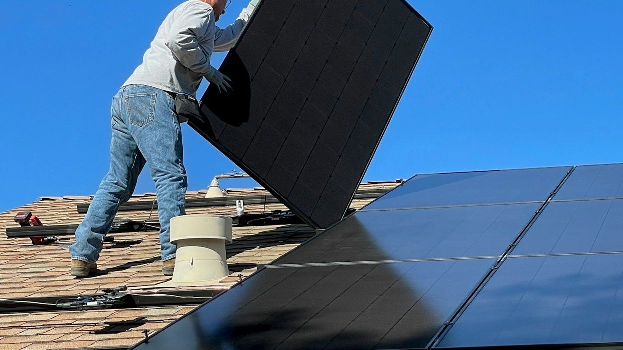 Man installing solar panels on house roof.