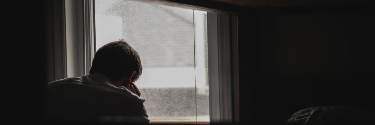 man looking outside window depression