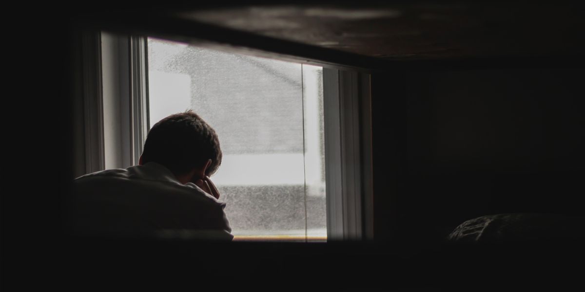 man looking outside window depression