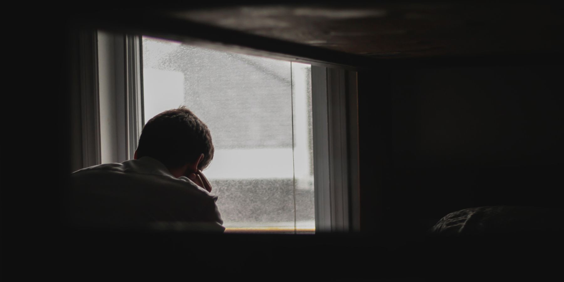 man looking outside window depression