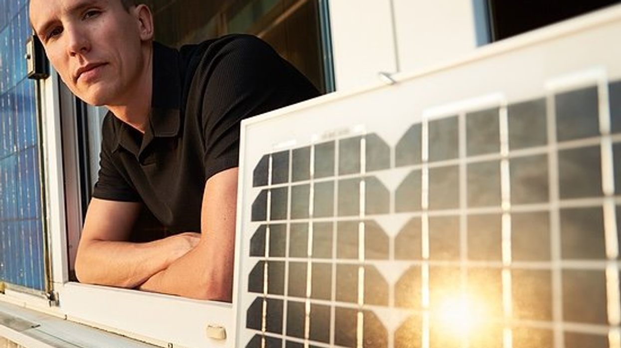 Man on balcony of residential building with solar panel