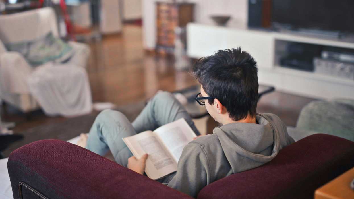 man sitting on sofa chair reading book.