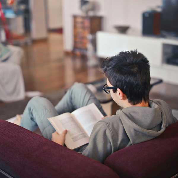man sitting on sofa chair reading book.