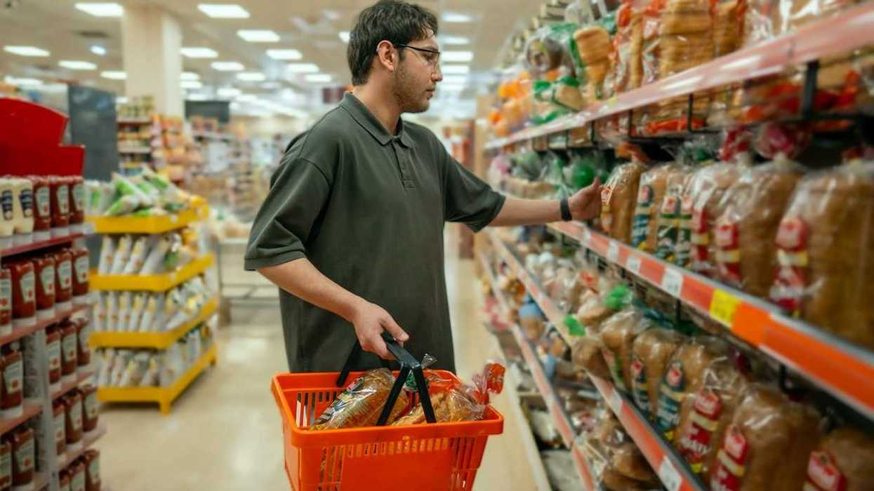 Man with grocery basket shopping for plastic-wrapped bread
