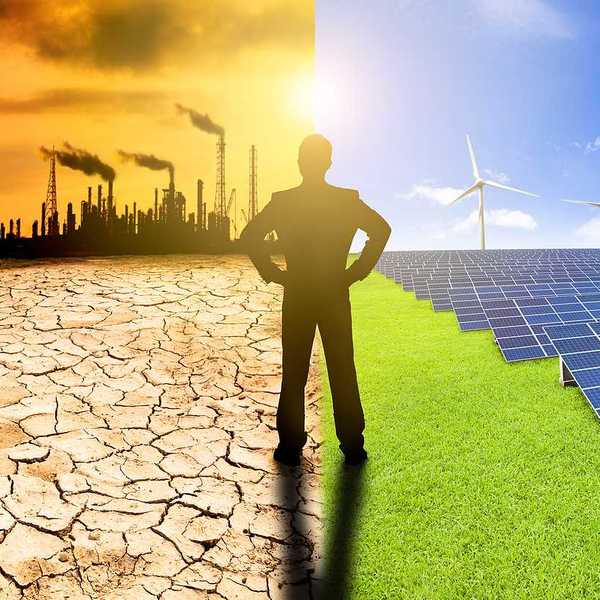 Man with hands on hips watching windmills solar panels and refinery spewing air pollution